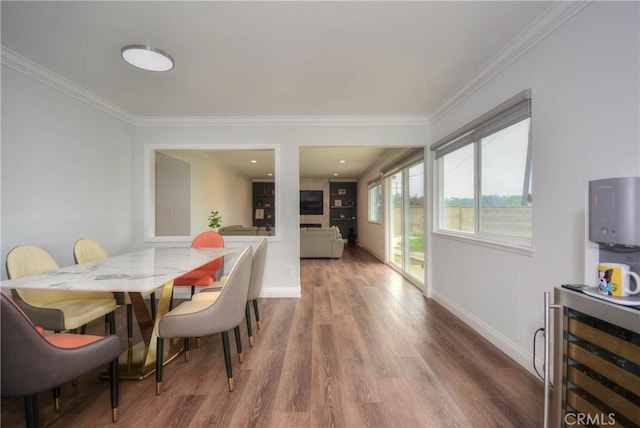 dining area with baseboards, wood finished floors, wine cooler, and ornamental molding