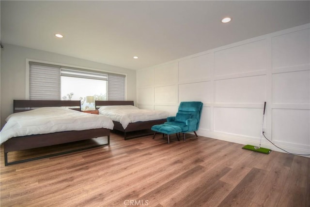bedroom with a decorative wall, light wood-style flooring, and recessed lighting
