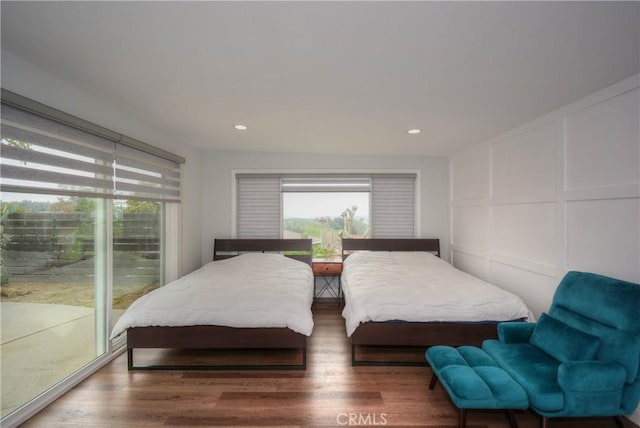 bedroom featuring recessed lighting, wood finished floors, and a decorative wall