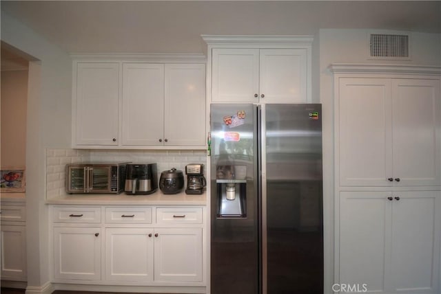 kitchen featuring light countertops, white cabinets, stainless steel fridge, and visible vents