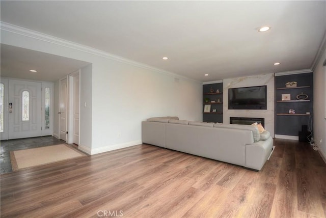 living area featuring baseboards, crown molding, wood finished floors, and built in shelves