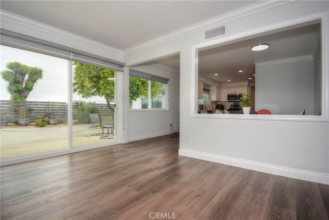 interior space with wood finished floors, ornamental molding, baseboards, and visible vents