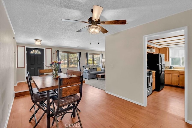 dining room with a ceiling fan, baseboards, light wood finished floors, and a textured ceiling