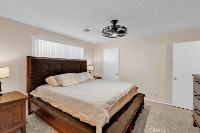 bedroom featuring visible vents, light colored carpet, a textured ceiling, and baseboards