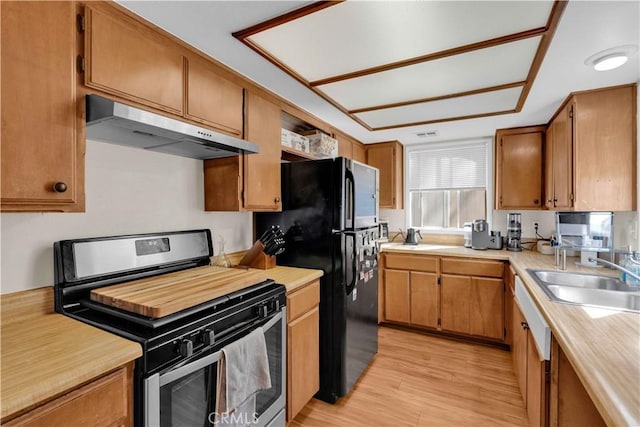 kitchen with under cabinet range hood, light countertops, stainless steel gas range, and a sink