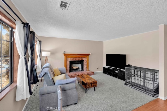 carpeted living area featuring a brick fireplace, a healthy amount of sunlight, visible vents, and baseboards