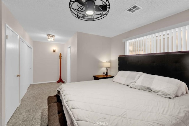 bedroom with visible vents, a textured ceiling, and carpet