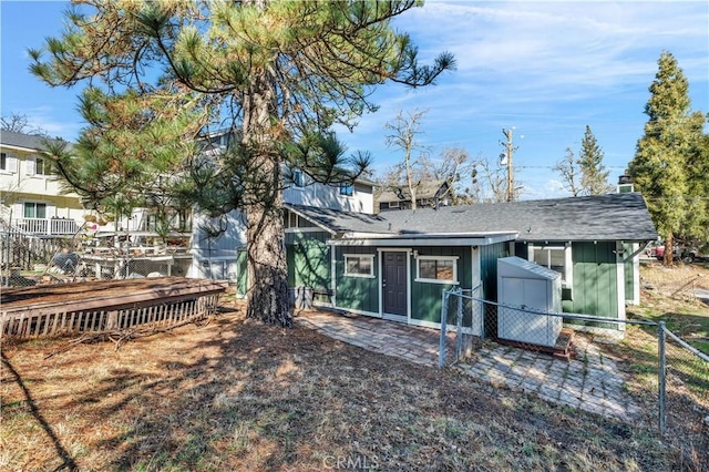 back of property featuring fence, a shed, roof with shingles, an outdoor structure, and board and batten siding