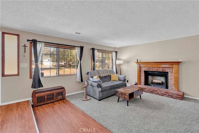 living room with visible vents, a brick fireplace, baseboards, and wood finished floors