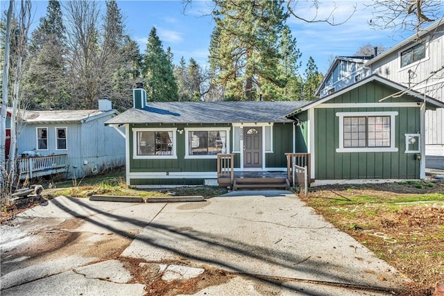 view of front of home featuring a shingled roof, board and batten siding, and a chimney