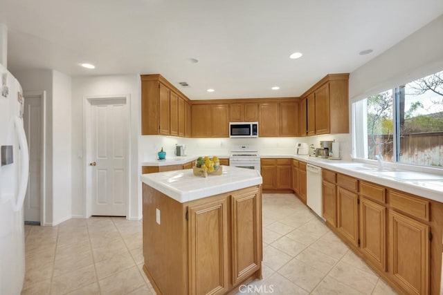 kitchen with a sink, a center island, recessed lighting, white appliances, and light tile patterned floors