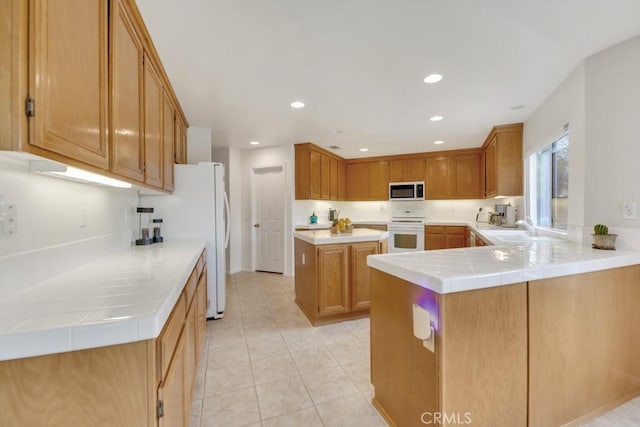 kitchen featuring a peninsula, recessed lighting, a sink, light countertops, and range