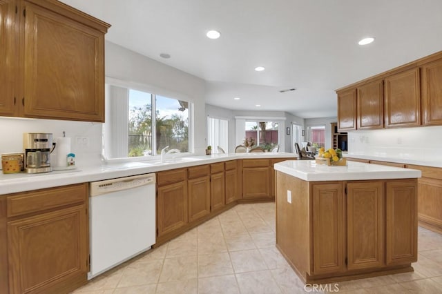 kitchen featuring light countertops, white dishwasher, and brown cabinets