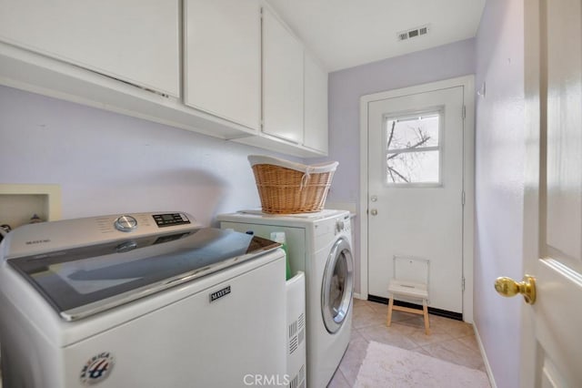 laundry area featuring visible vents, baseboards, washer and clothes dryer, light tile patterned floors, and cabinet space