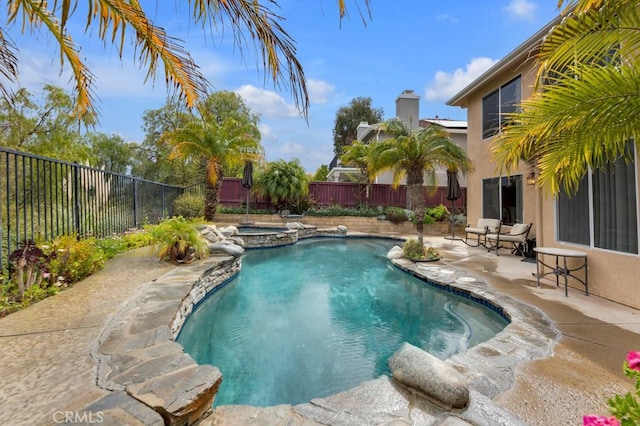 view of pool featuring a patio, a pool with connected hot tub, and a fenced backyard