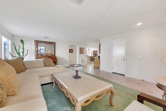 living room featuring visible vents, baseboards, light tile patterned floors, recessed lighting, and arched walkways