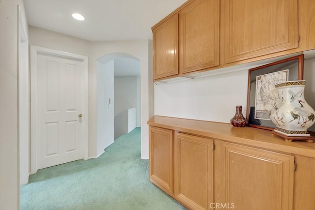 hallway with recessed lighting, arched walkways, and light colored carpet