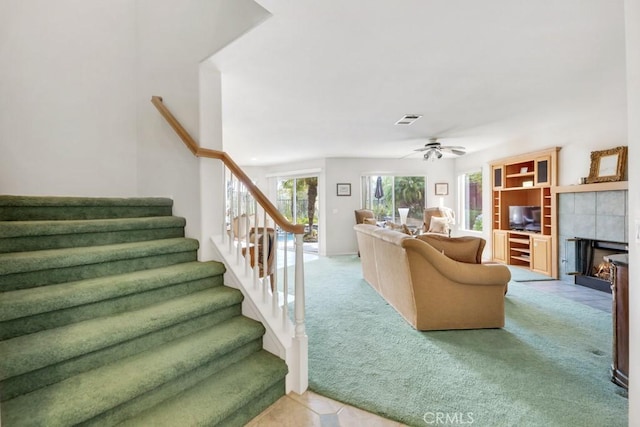 living room with visible vents, light colored carpet, stairs, and ceiling fan