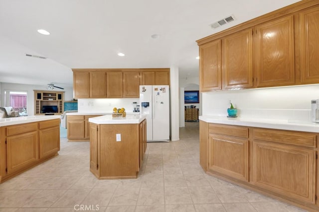 kitchen with visible vents, a center island, light countertops, white fridge with ice dispenser, and arched walkways