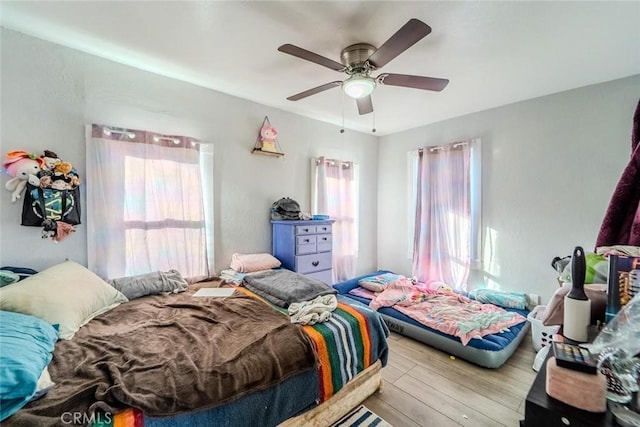 bedroom with a ceiling fan, multiple windows, and wood finished floors
