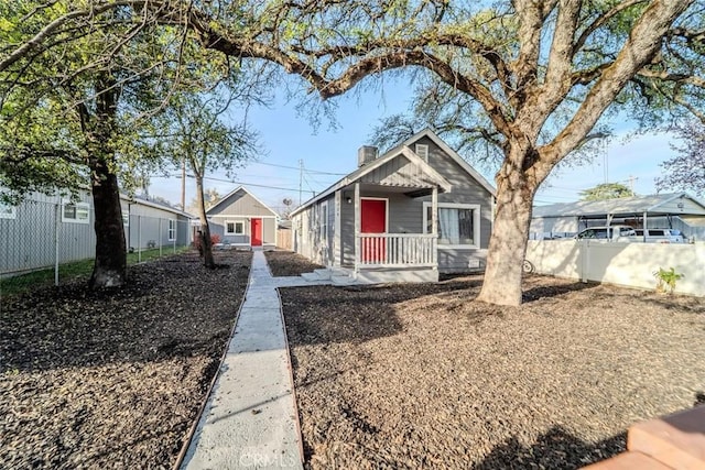 bungalow-style home with a porch, a chimney, and fence