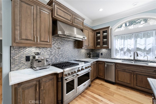 kitchen featuring range with two ovens, ornamental molding, decorative backsplash, a sink, and under cabinet range hood