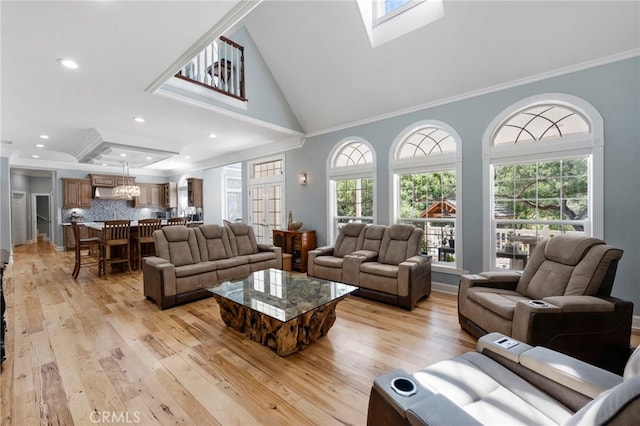 living area featuring plenty of natural light, crown molding, and light wood-style floors