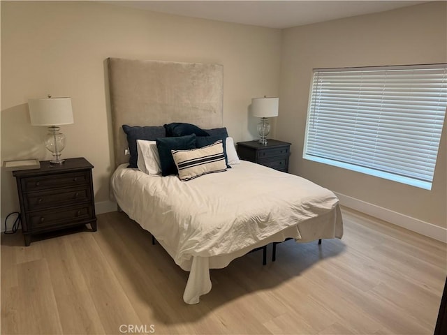 bedroom featuring light wood-style floors and baseboards