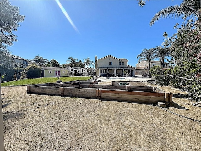 rear view of house featuring a lawn and a vegetable garden