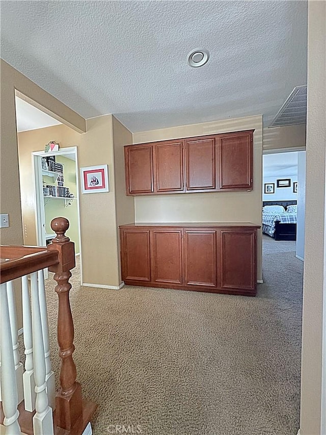 corridor featuring a textured ceiling, baseboards, and carpet floors