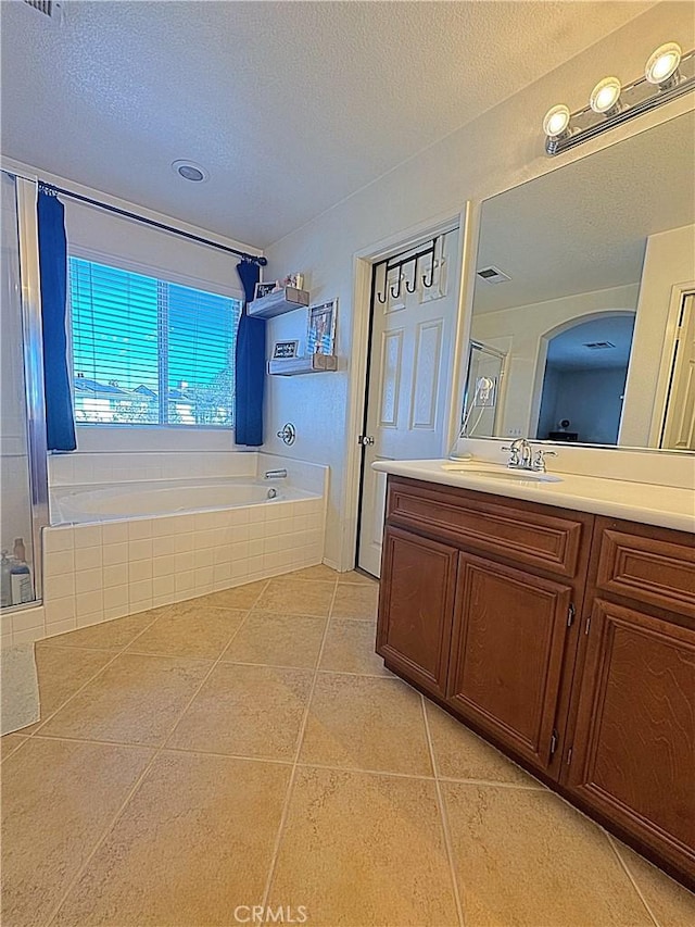 bathroom featuring vanity, tile patterned flooring, a shower stall, a textured ceiling, and a bath