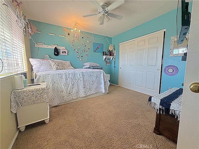 carpeted bedroom featuring ceiling fan with notable chandelier and a closet