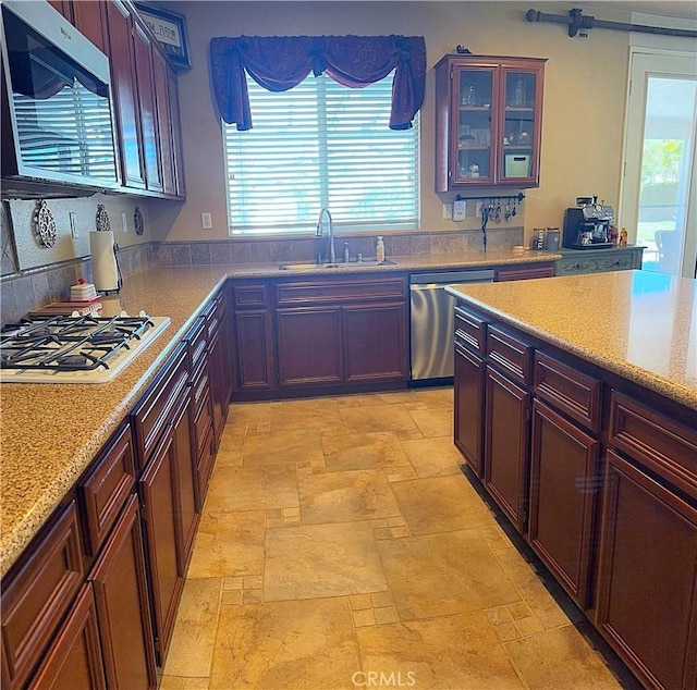 kitchen with a sink, stone finish floor, a healthy amount of sunlight, and stainless steel appliances