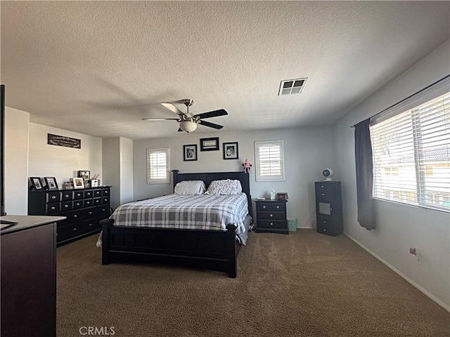 bedroom featuring multiple windows, visible vents, dark colored carpet, and a textured ceiling