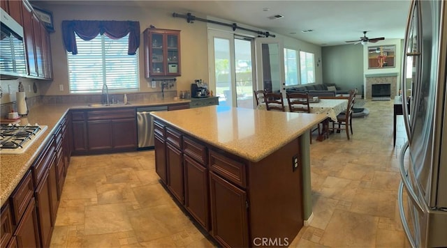 kitchen featuring a sink, stainless steel appliances, stone tile floors, and ceiling fan