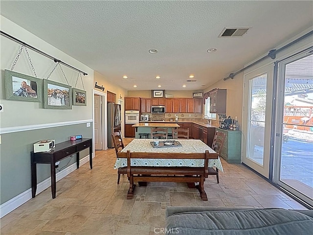 dining room featuring visible vents, stone finish flooring, a textured ceiling, recessed lighting, and baseboards