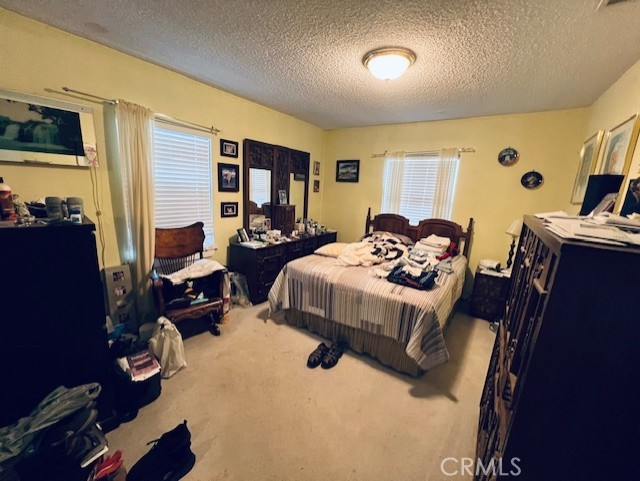 carpeted bedroom with visible vents and a textured ceiling