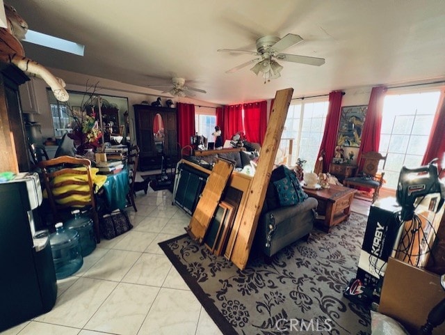 living area with light tile patterned floors, plenty of natural light, and a ceiling fan