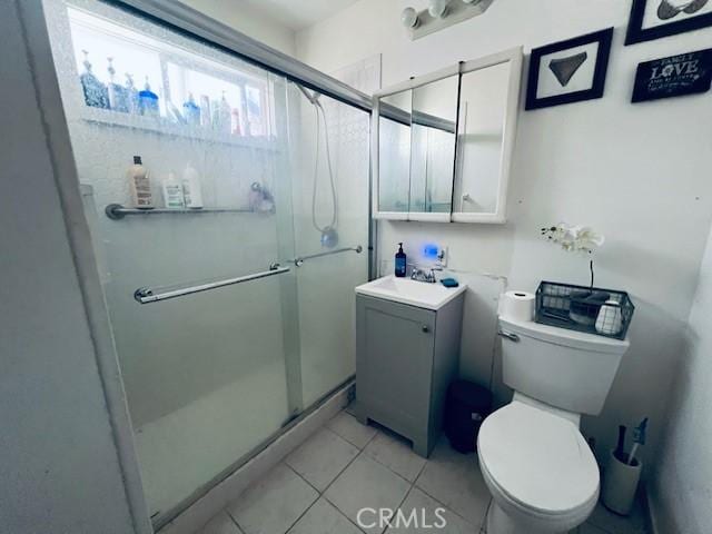 bathroom with toilet, a stall shower, vanity, and tile patterned flooring