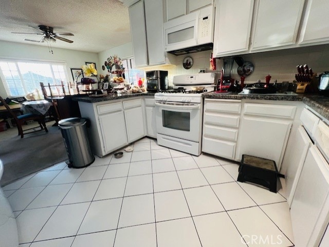 kitchen featuring white appliances, a ceiling fan, a peninsula, a textured ceiling, and dark countertops