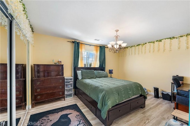 bedroom featuring a notable chandelier, wood finished floors, visible vents, and baseboards