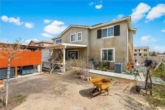 back of property featuring cooling unit, fence, and stucco siding