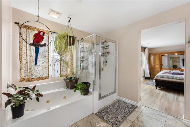 ensuite bathroom with tile patterned floors, a stall shower, ensuite bath, a tub with jets, and baseboards