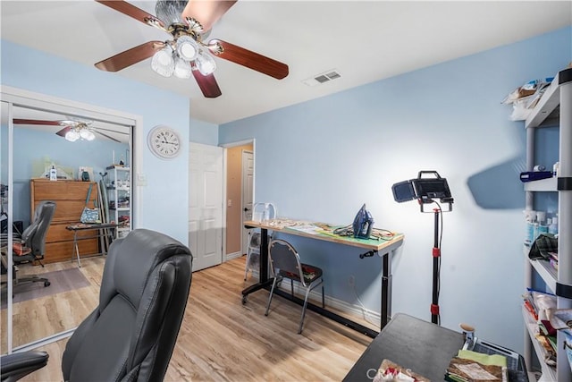 home office with a ceiling fan, visible vents, and light wood-type flooring