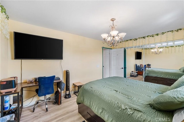 bedroom featuring light wood finished floors, a notable chandelier, and baseboards