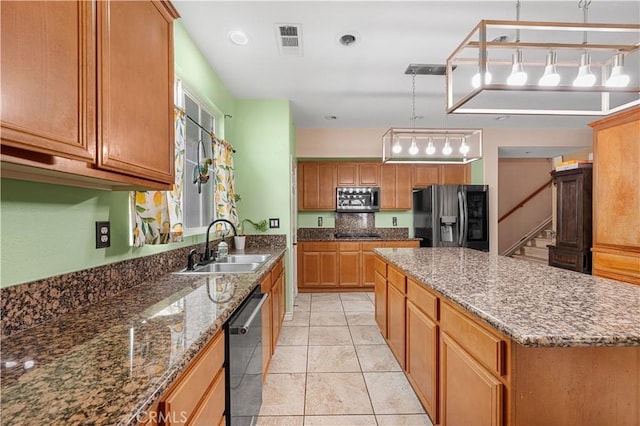 kitchen featuring visible vents, a sink, a kitchen island, dark stone counters, and appliances with stainless steel finishes