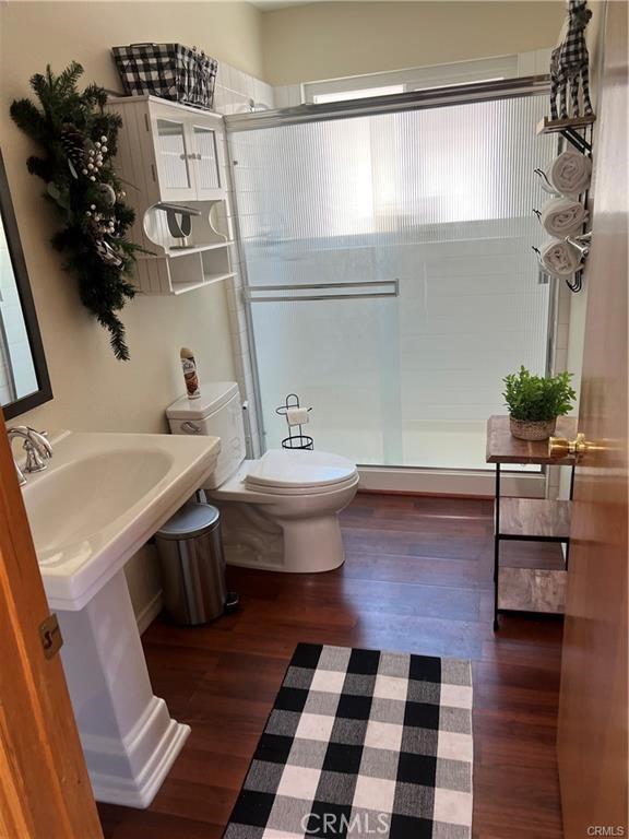 bathroom with a shower stall, toilet, and wood finished floors