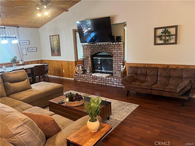 living area with a wainscoted wall, lofted ceiling, wood finished floors, and a ceiling fan