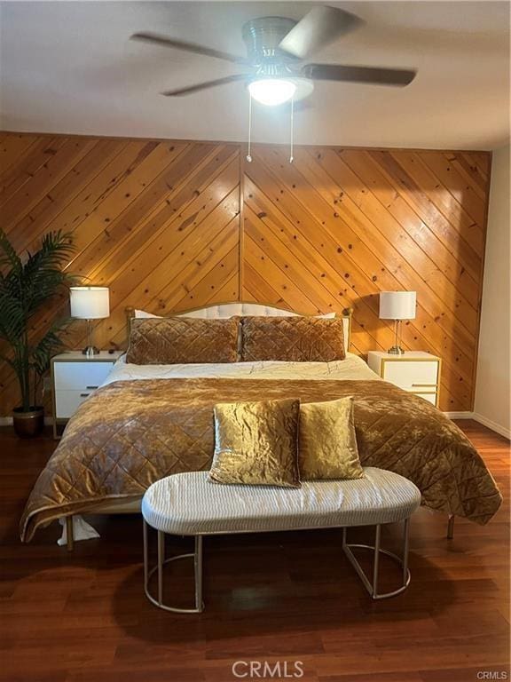 bedroom featuring wooden walls, wood finished floors, and ceiling fan