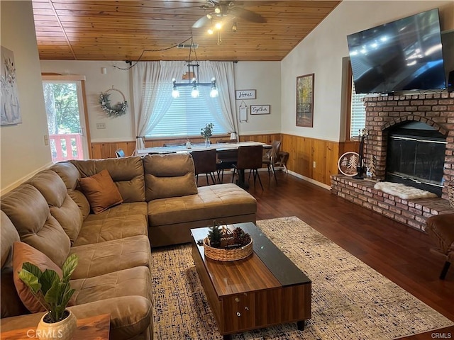 living area with ceiling fan, a wainscoted wall, wood walls, wood ceiling, and wood finished floors